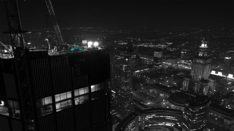 Nocna praca żurawia na wysokości nad panoramą miasta